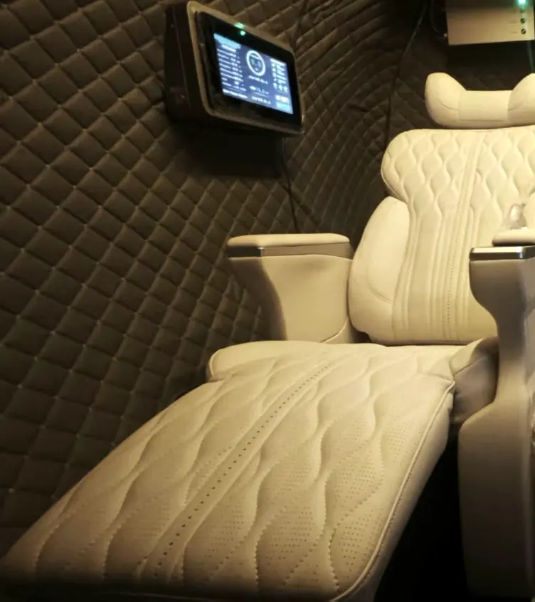 Quilted ivory captain's seat in full recline, with control screen on the quilted wall